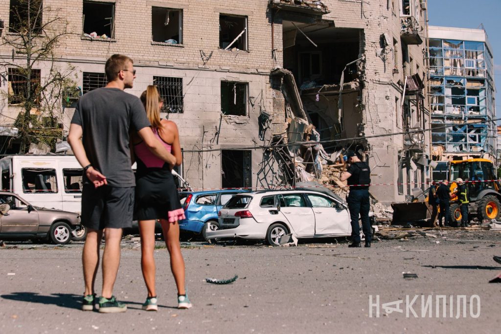 пара на фоні зруйнованого будинку