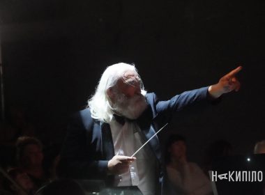 a man with long hair and a white beard holding a baton