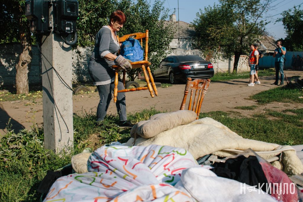 Жінка несе меблі після обстрілу