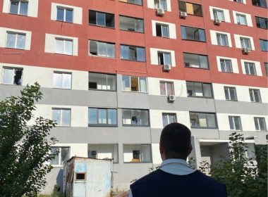 Співробітник облпрокуратури дивиться на пошкоджену багатоповерхівку