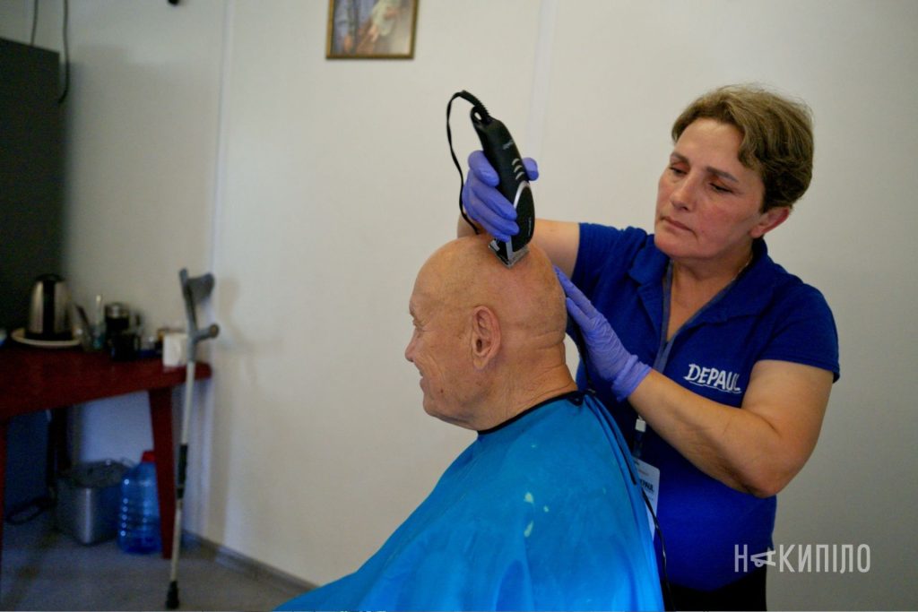 Волонтерка благодійної організації підстригає чоловіка