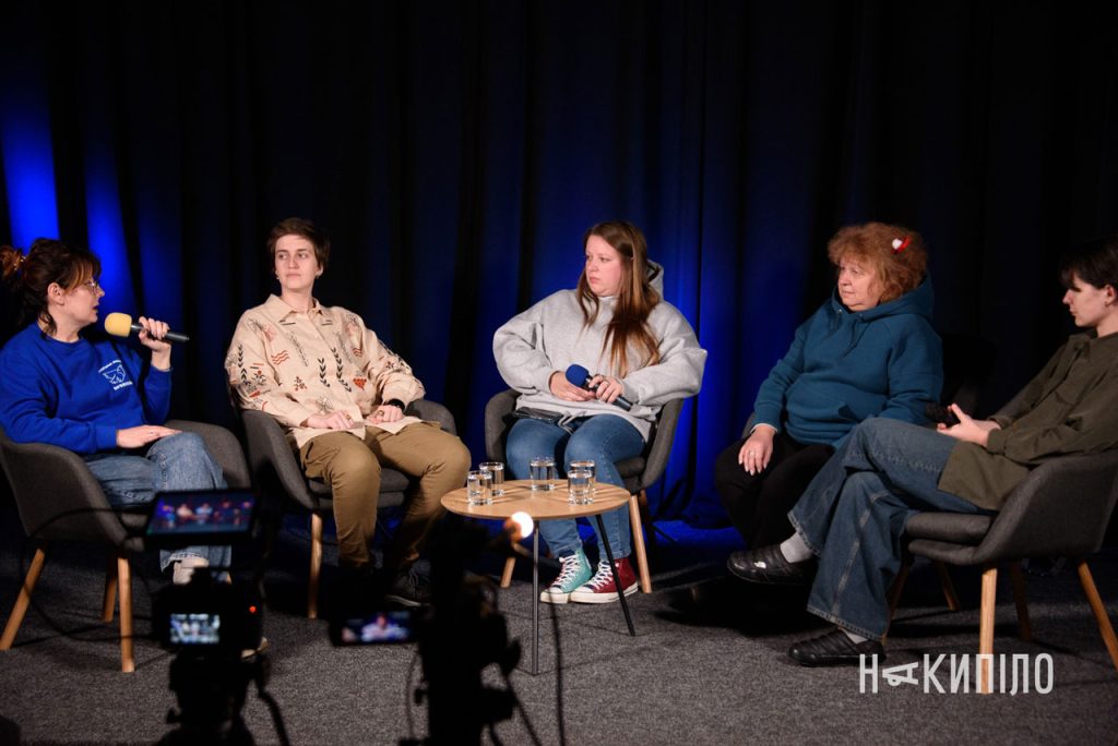 16 П'ятеро осіб сидять у кріслах перед камерами під час зустрічі з волонтерками в пресцентрі «Накипіло».