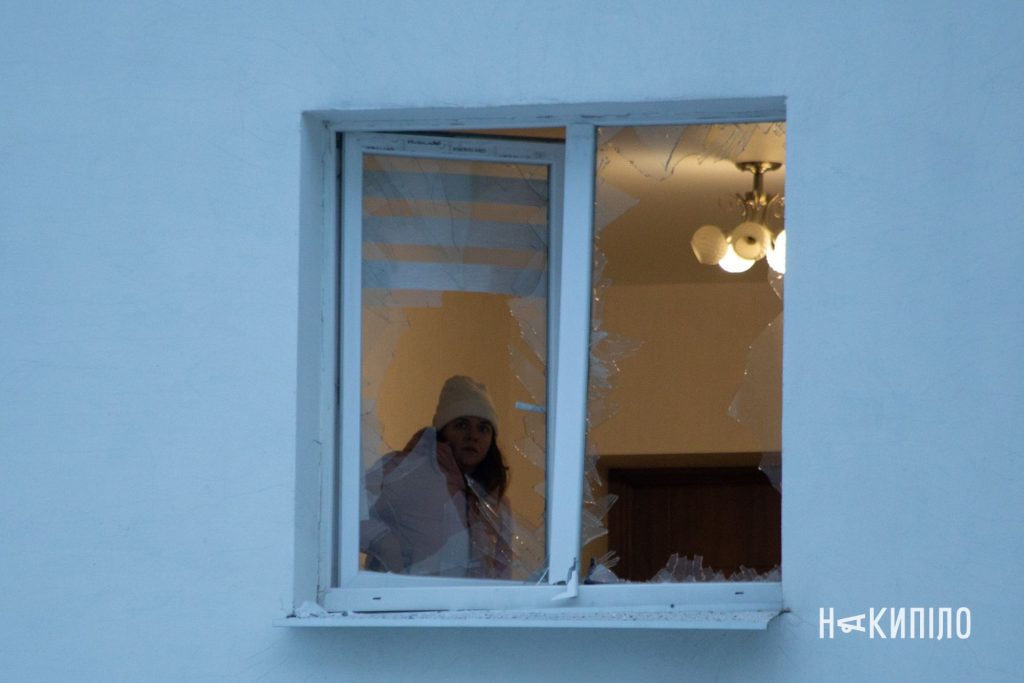 20 дронів і ракета: наслідки ударів по Харкову 10 дівчина дивиться у вікно з вибитим склом після обстрілу