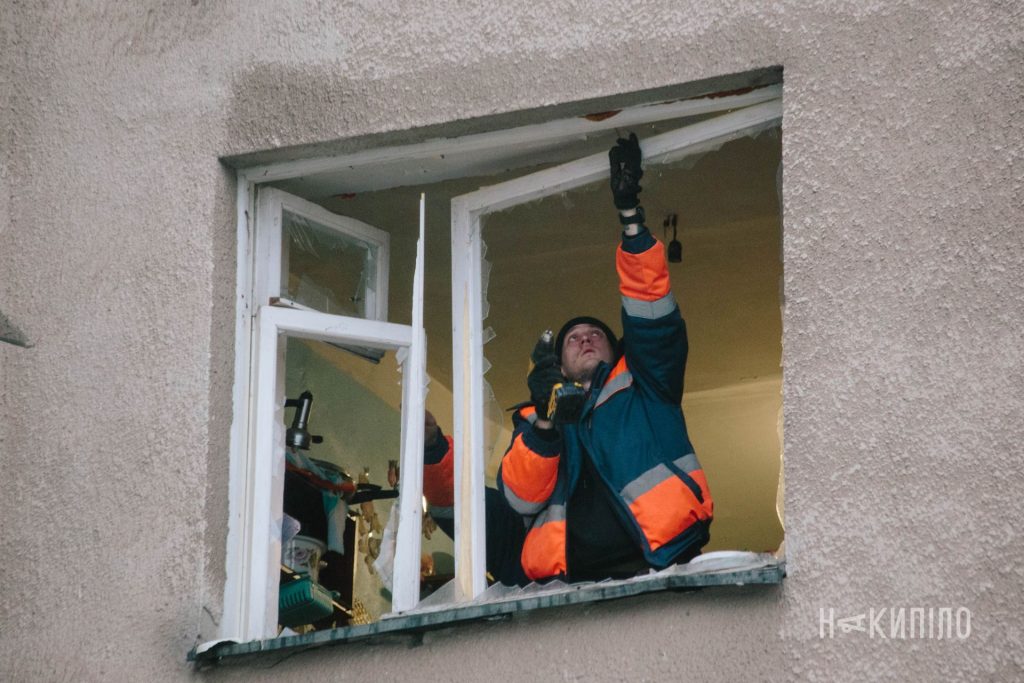 Наслідки масованої атаки на Харків чоловік лагодить віконну раму після обстрілу