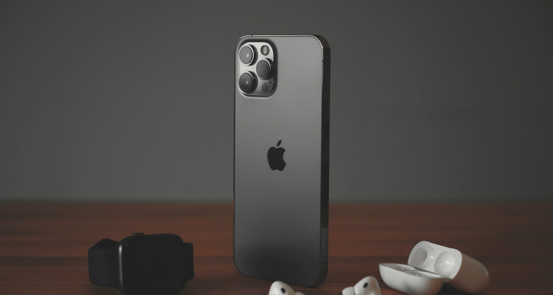 iPhone 18 Pro сірого кольору, поряд навушники і епл вотч