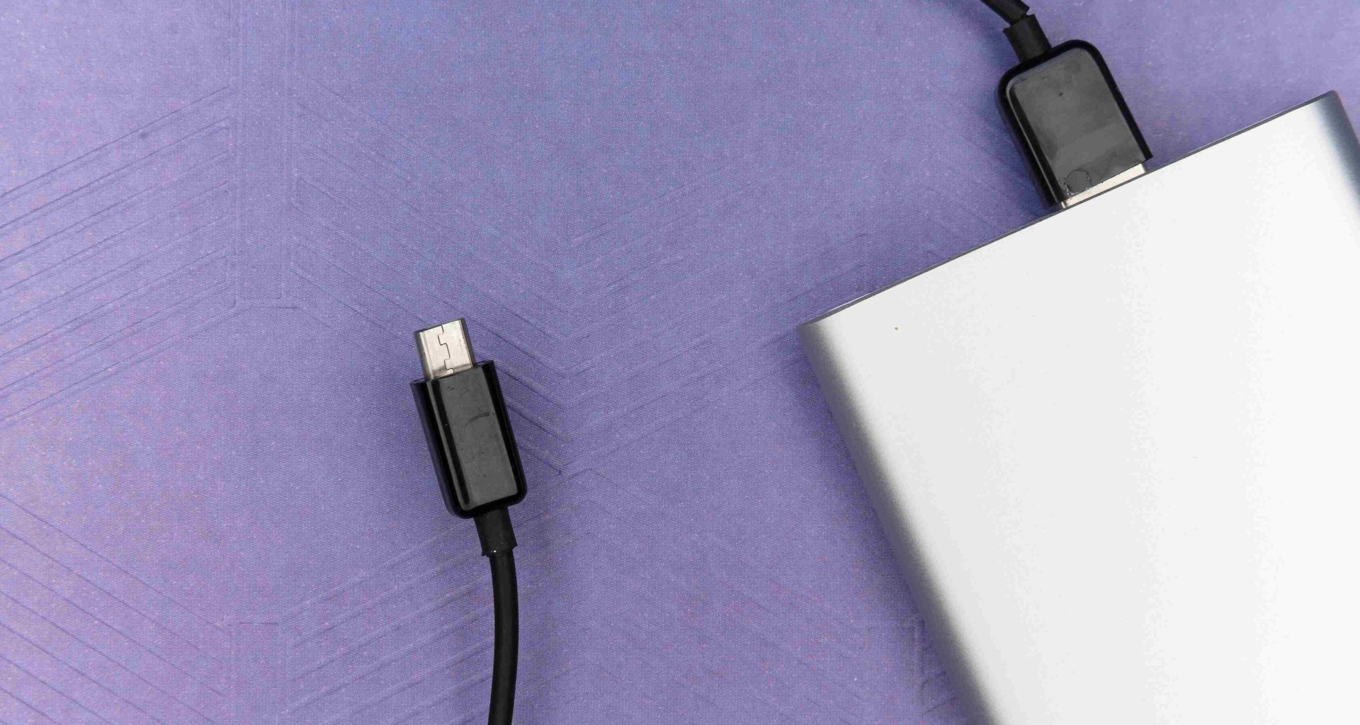 повербанк сріблястого кольору із чорним кабелем мікро usb