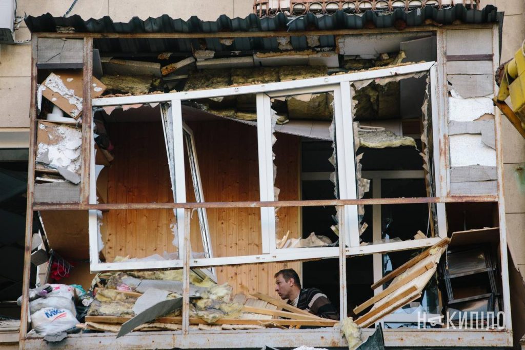 росіяни атакували пам'ятку містобудування та архітектури в Харкові: фото Пошкоджена віконна рама, за яко. стоїть чоловік, Шевченківський район Харкова