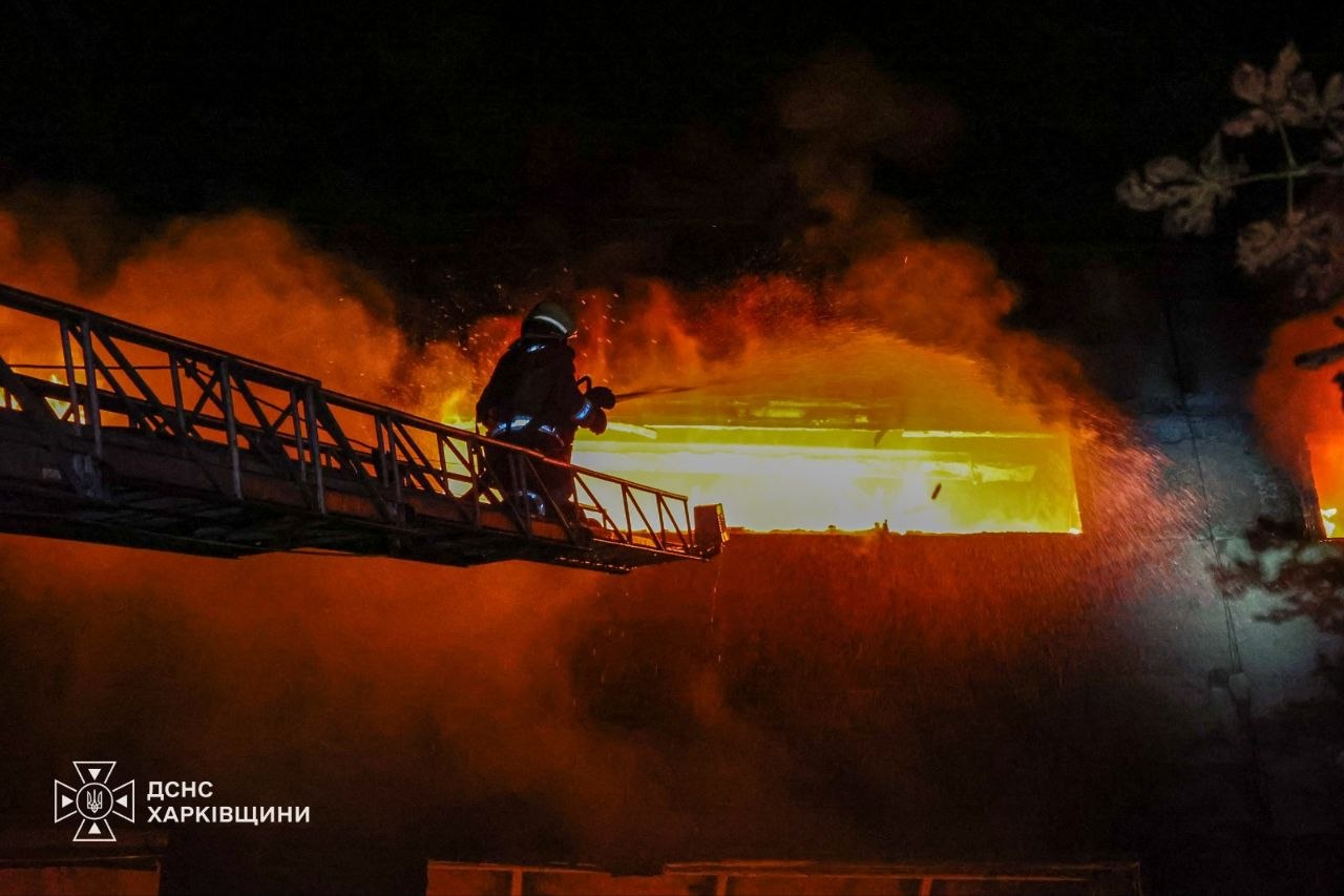 Пожежник вночі гасить велику пожежу на підприємстві після обстрілу.